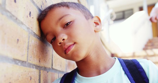 Young Boy Leaning Against Brick Wall with Pensive Expression - Download Free Stock Images Pikwizard.com