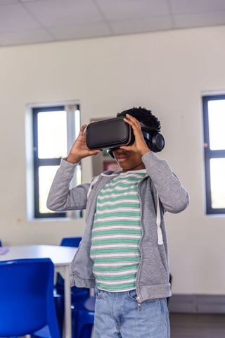 African american teen exploring virtual reality learning in classroom with vr headset
