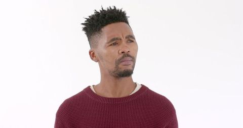 Man in red sweater contemplating ideas against white background