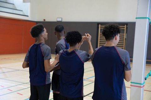 African american teen athletes standing together near court pole in school gym