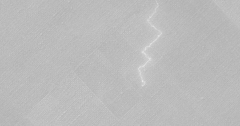 Macro gray woven fabric showing bright zigzag mark and subtle patch texture