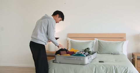Man Packing Clothes in Bedroom, Preparing for Journey or Staycation