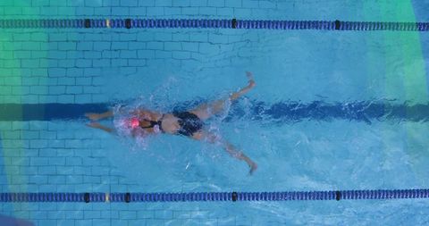 Female athlete exercising in lap pool with pink swim cap