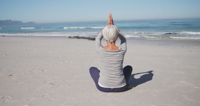 Senior caucasian woman doing yoga and meditating on beach. Senior lifestyle, realxation, nature, free time and vacation.