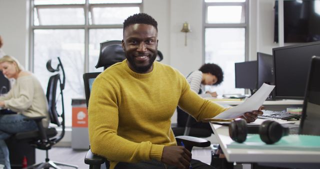 Portrait of smiling african american creative businessman sitting by desk in modern office. business and office work environment.