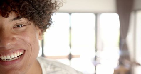 Smiling Young Man with Curly Hair in Bright Room
