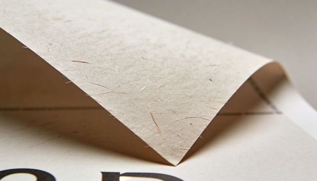 Curled natural fiber paper showing subtle fibers, parchment texture and bold type macro