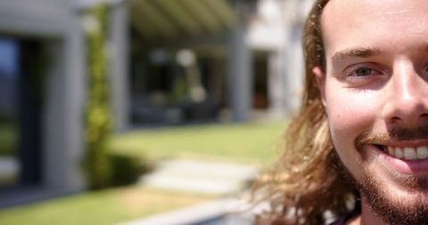 Smiling man with long hair relaxing outdoors