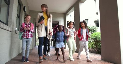 Female Teacher Guiding Students Outdoors with Backpack Learning