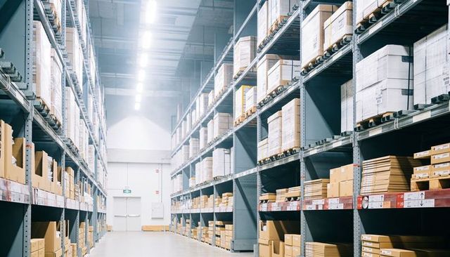 Industrial warehouse aisle with towering pallet racks and organized cardboard pallets