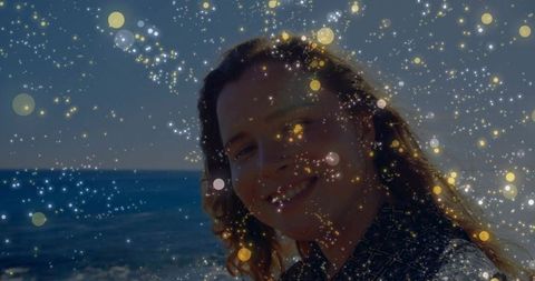Smiling woman by beach with glittering sparkles in air