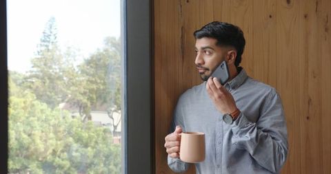 Professional Man Using Smartphone by Window with Coffee Mug