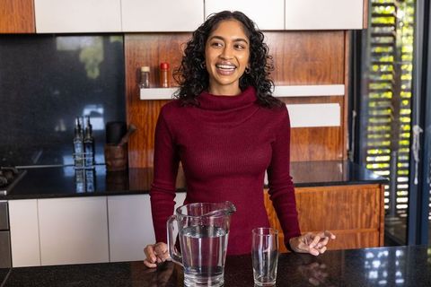 Smiling woman in modern kitchen with water pitcher