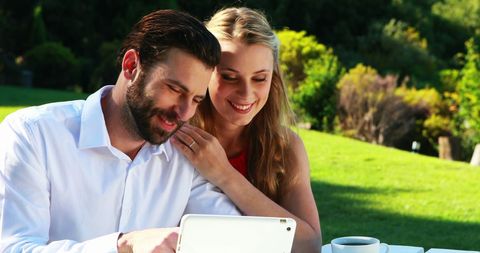 Young Happy Couple Using Tablet in Outdoor Garden Setting