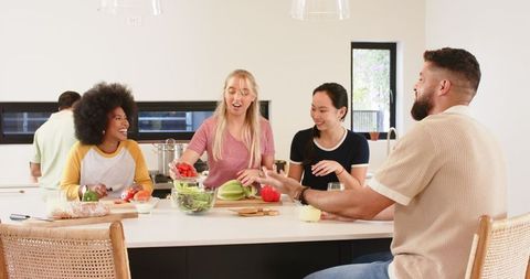 Diverse Friends Collaborating in Modern Kitchen Preparing Salad