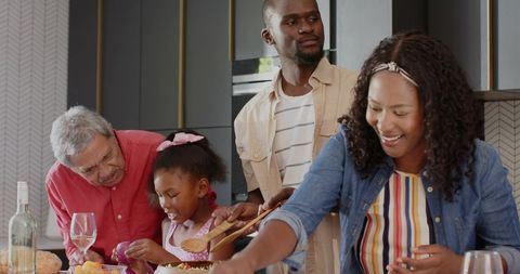 Multigenerational family preparing and serving meal on modern kitchen island, sharing warmth