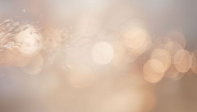 Glowing golden bokeh surrounding soft center light with sparkling particles
