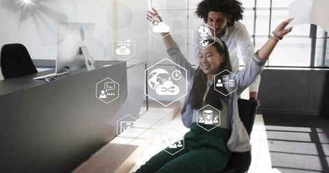 Team celebrating cloud analytics win while pushing swivel chair in modern office