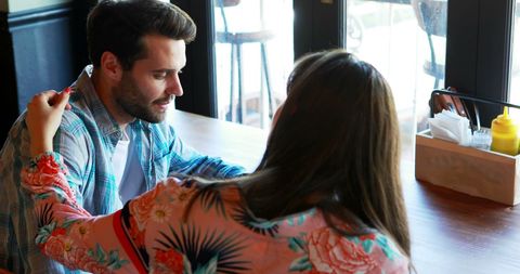 Woman Consoling Upset Man at Cafe Table in Calm Environment