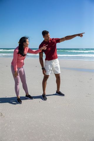 Diverse couple enjoying coastal adventure on sunny beach