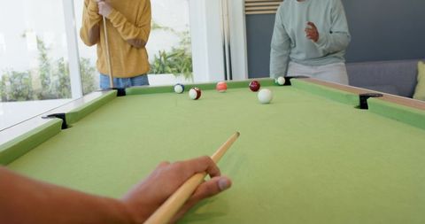 Playing pool together in bright living room with glass doors and casual style