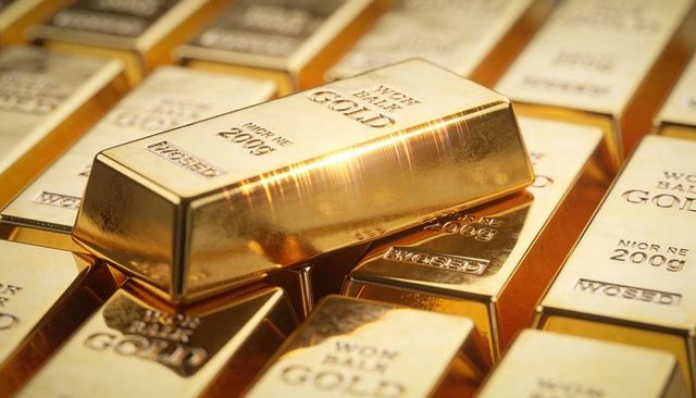 Glinting gold bullion bar resting diagonally on stacked ingots, polished luxury wealth close-up