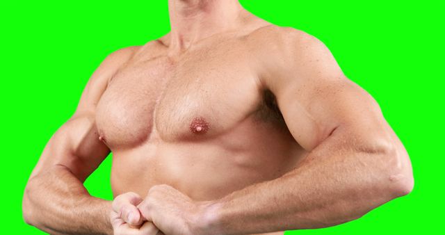 Muscular man showing his defined chest and arm muscles. Popular in fitness blogs, health and wellness magazines, strength training advertisements, bodybuilding promotions. Green background allows easy removal and replacement with different backdrops.