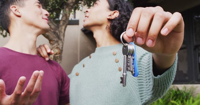 Happy diverse male moving house, holding keys, embracing and smiling. Spending quality time at home.