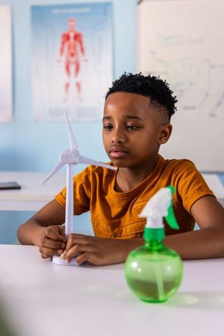 African american preteen holding wind turbine during classroom renewable energy project