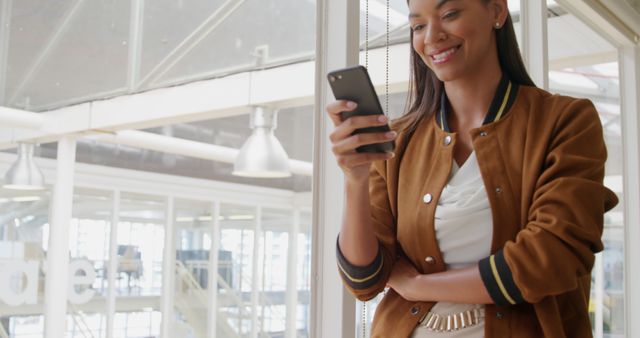 Young businesswoman smiling while using smartphone in modern office - Download Free Stock Images Pikwizard.com