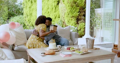 African American Couple Sharing Gifts on Sunny Patio Celebration