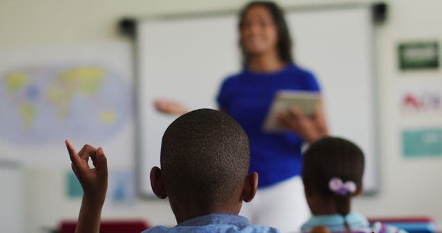 African american boy sitting in classroom raising hand to answer questions during lesson - Download Free Stock Photos Pikwizard.com