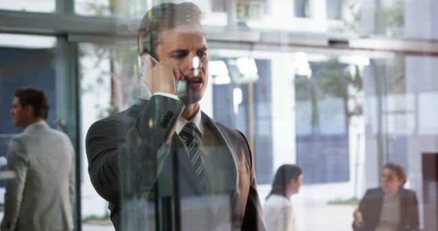 Businessman discussing on smartphone in modern office lobby - Download Free Stock Images Pikwizard.com