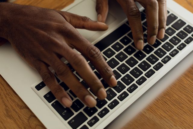 Close up view of the hands of an African-American man using a laptop on a table