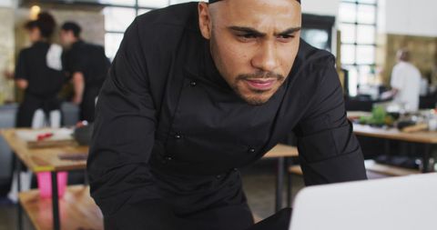 Focused Male Chef Using Laptop in Professional Kitchen