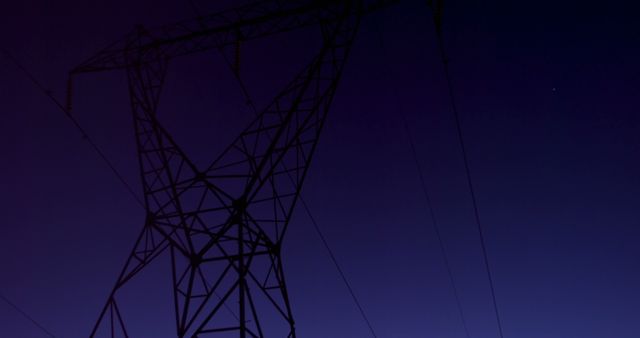 Silhouette of a high voltage transmission tower against a fading twilight sky. Useful for topics on energy infrastructure, electricity distribution, and dusk scenery creating dramatic effects. Can be used in articles about power grids, energy efficiency, and maintaining sustainable power solutions.