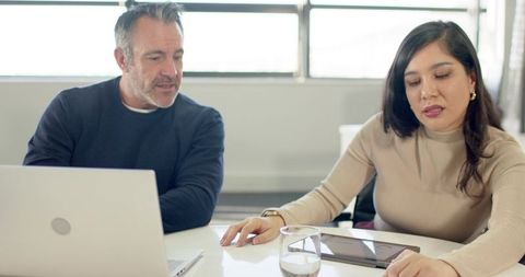 Diverse colleagues discussing strategy at desk with laptop and tablet