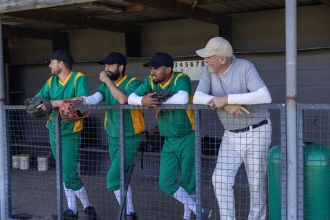Baseball team leaning in dugout with coach signaling strategy and animated play diagram