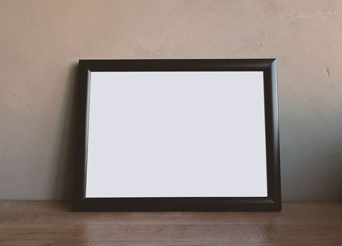 Empty frame on wooden table with concrete wall background