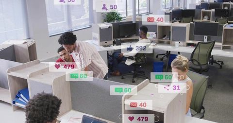 Coworkers collaborating and reviewing monitor in open-plan office with notification overlays