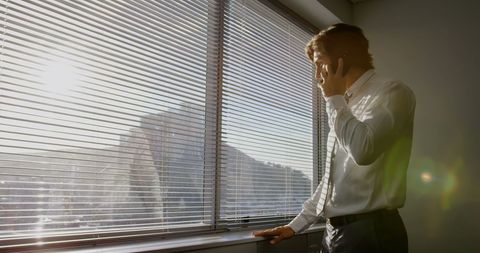 Young Executive Talking on Mobile Phone by Office Window - Download Free Stock Images Pikwizard.com