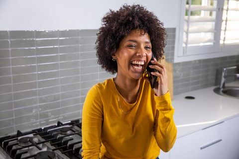 Cheerful Woman Laughing on Phone in Modern Kitchen