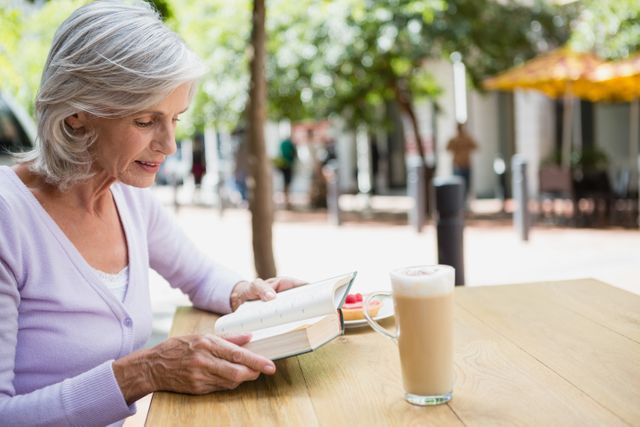 Senior woman reading a book in outdoor cafÃ©