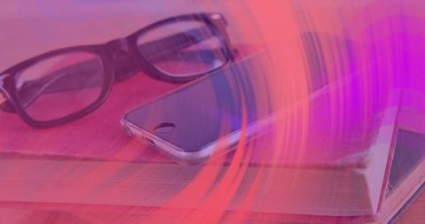 Pink light swirl sweeping over smartphone on notebooks with glasses and wooden desk