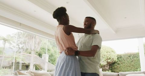 Joyful young couple dancing at home in living room