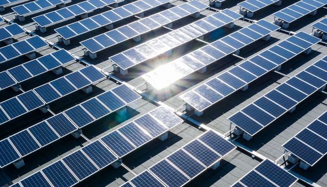 Rooftop Solar Array Forming Geometric Grid Reflecting Sunlight on Flat Industrial Roof