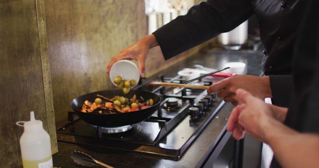 Professional Chef Adding Olives to Sizzling Gourmet Dish in Modern Kitchen - Download Free Stock Images Pikwizard.com