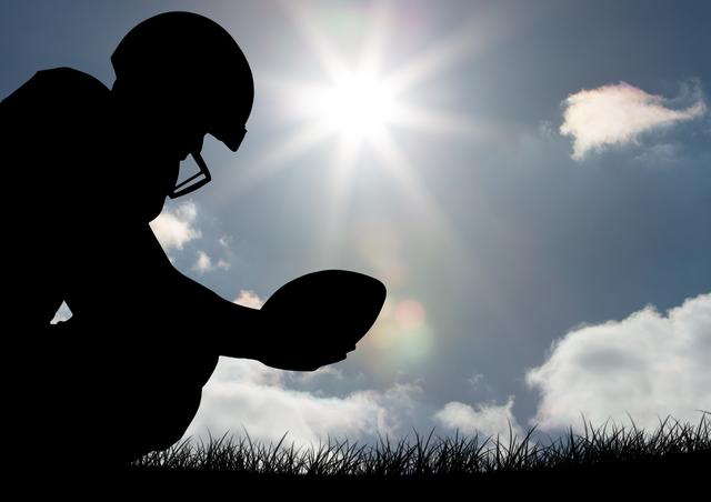 Silhouette of an athlete holding a rugby ball under bright sunlight in the outdoors. Suitable for rugby promotions, sports motivation posters, fitness campaigns, outdoor activity advertisements, and articles about determination and sportsmanship.
