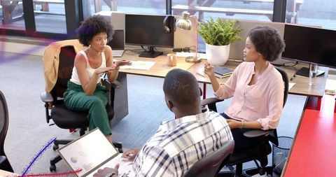 Colleagues Collaborating in Open-Plan Office Discussing Laptop Data and Project Strategy