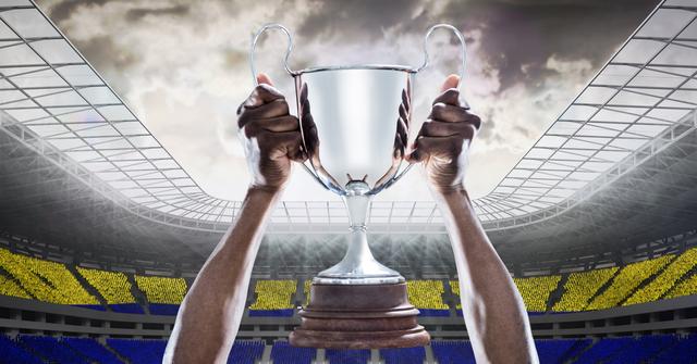 Hands holding a trophy high in front of a crowd in a large stadium. Perfect for concepts related to victory, sports achievements, championships, and accomplishments.